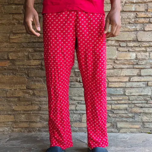 A pair of red pajama pants with white polka dots worn by a person.