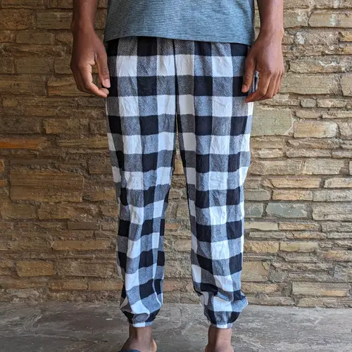 A person wearing checkered lounge pants with a gray top.