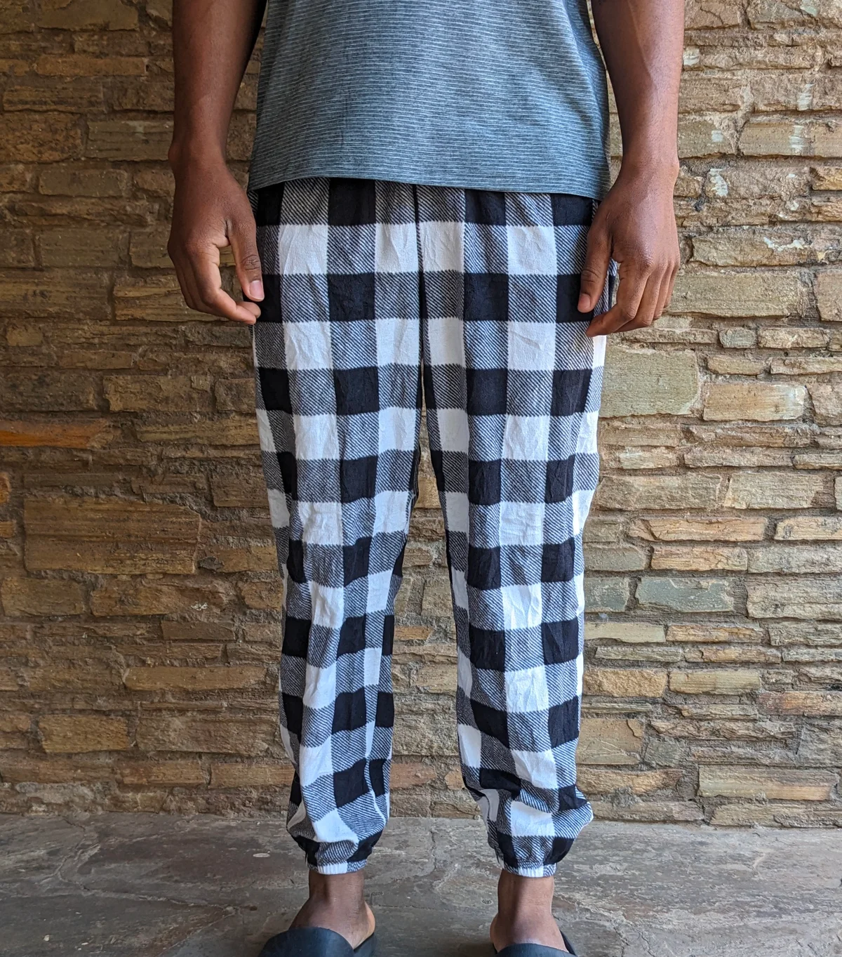 A person wearing checkered lounge pants with a gray top.