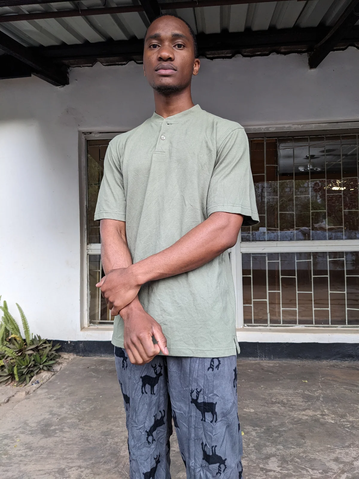 A young man wearing a casual olive green short-sleeve tee.