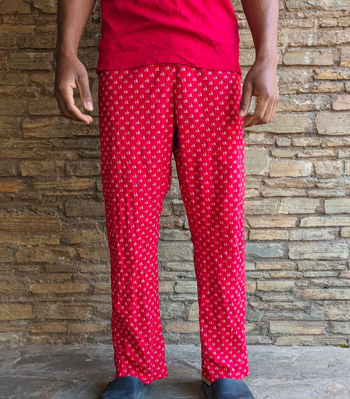 A pair of red pajama pants with white polka dots worn by a person.