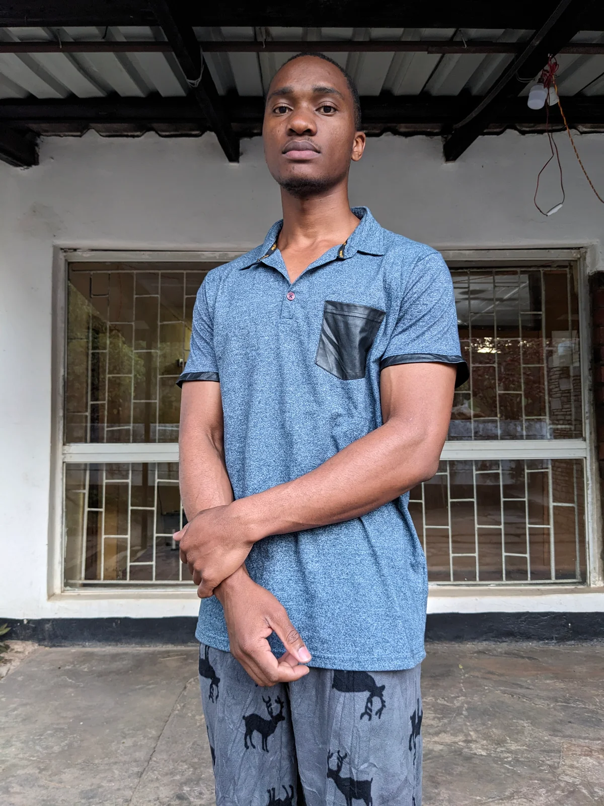 A man wearing a blue polo shirt with a black pocket, standing outdoors.
