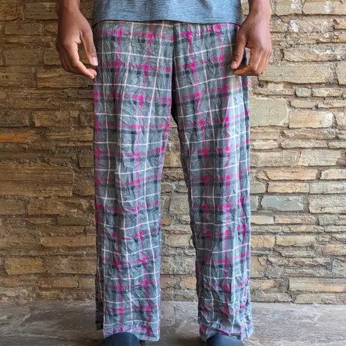 A man wearing plaid lounge pants with gray and pink colors.