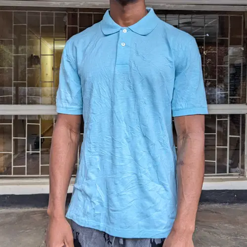 A man wearing a cool blue polo shirt standing outdoors.