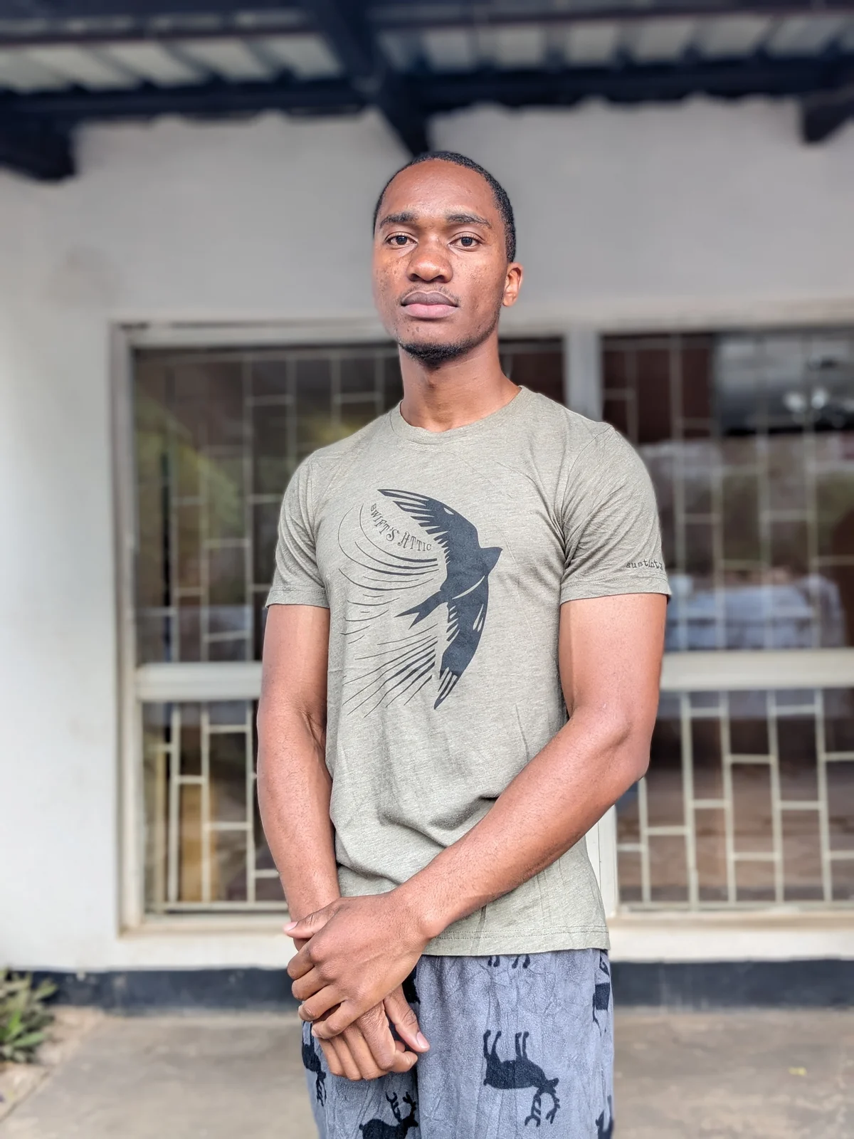 A man wearing a light green t-shirt with a bird graphic design.