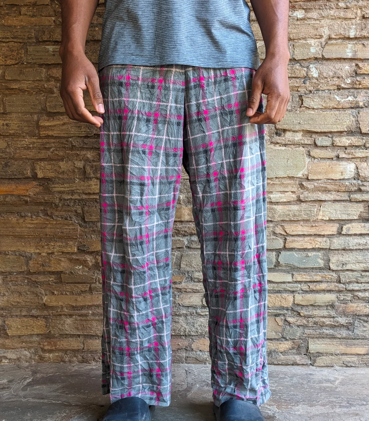 A man wearing plaid lounge pants with gray and pink colors.