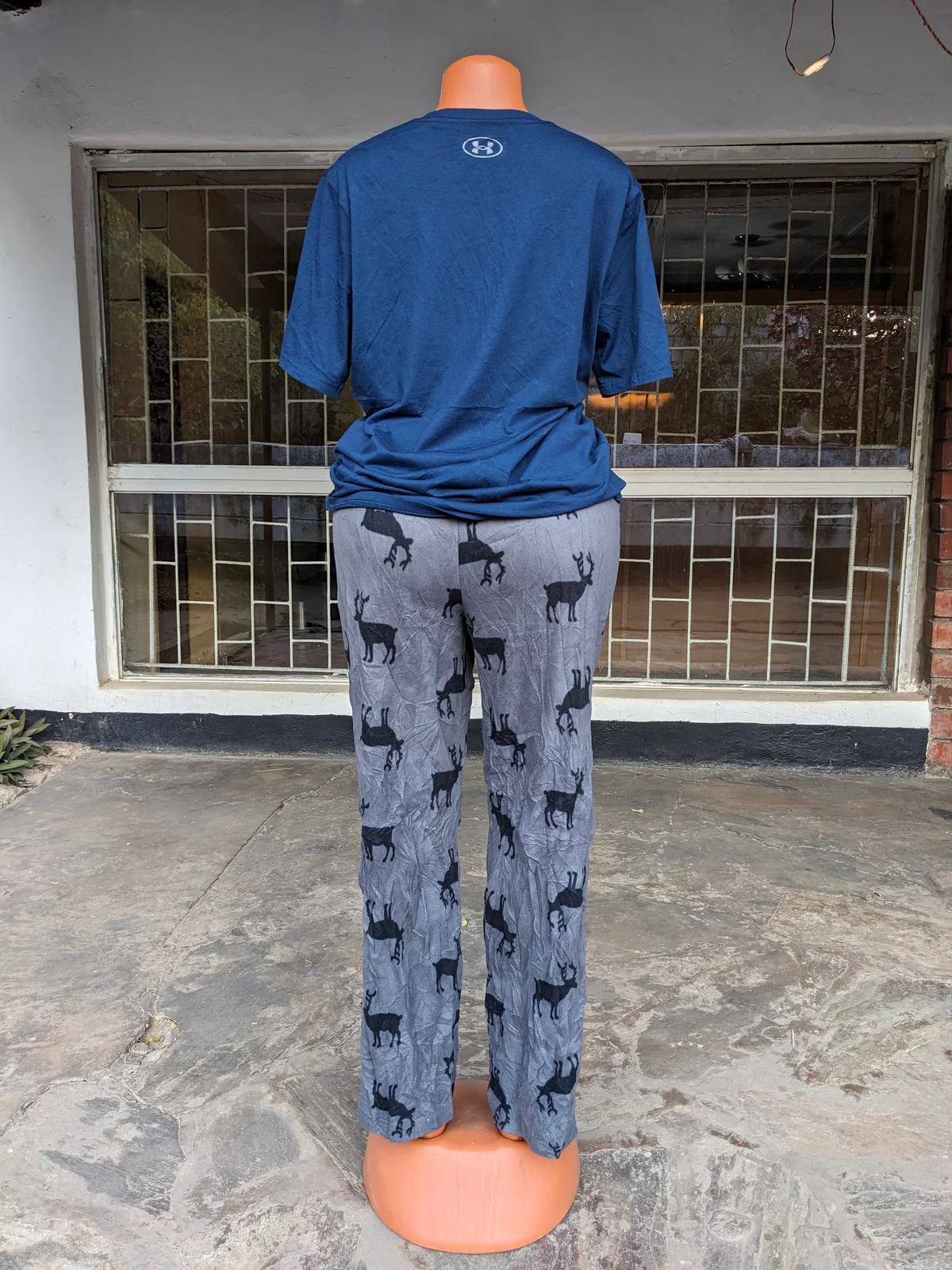 A mannequin wearing a blue t-shirt and gray pajama pants with animal prints.