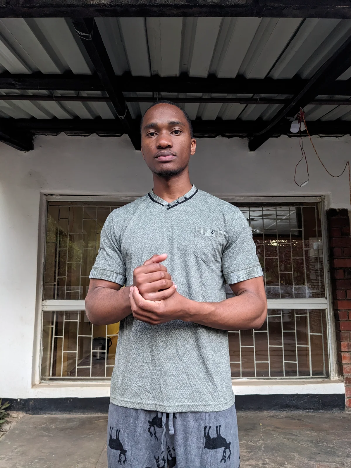 A man wearing a grey casual t-shirt, standing outdoors.