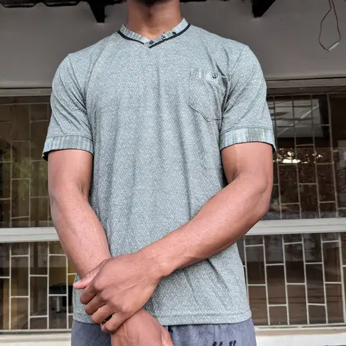A man wearing a grey casual t-shirt, standing outdoors.