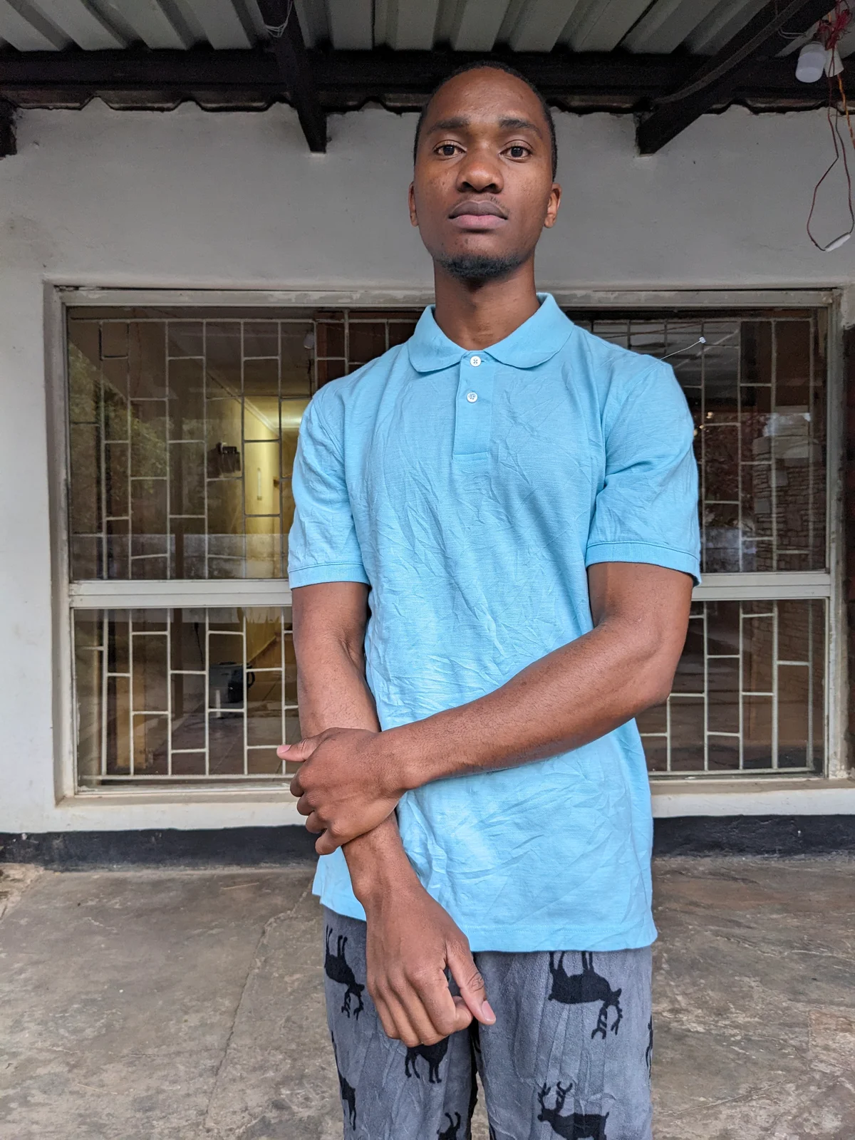 A man wearing a cool blue polo shirt standing outdoors.